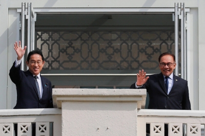 Prime Minister Fumio Kishida waves with Malaysian leader Anwar Ibrahim during his official visit to Malaysia, in Putrajaya, outside Kuala Lumpur, on Sunday.