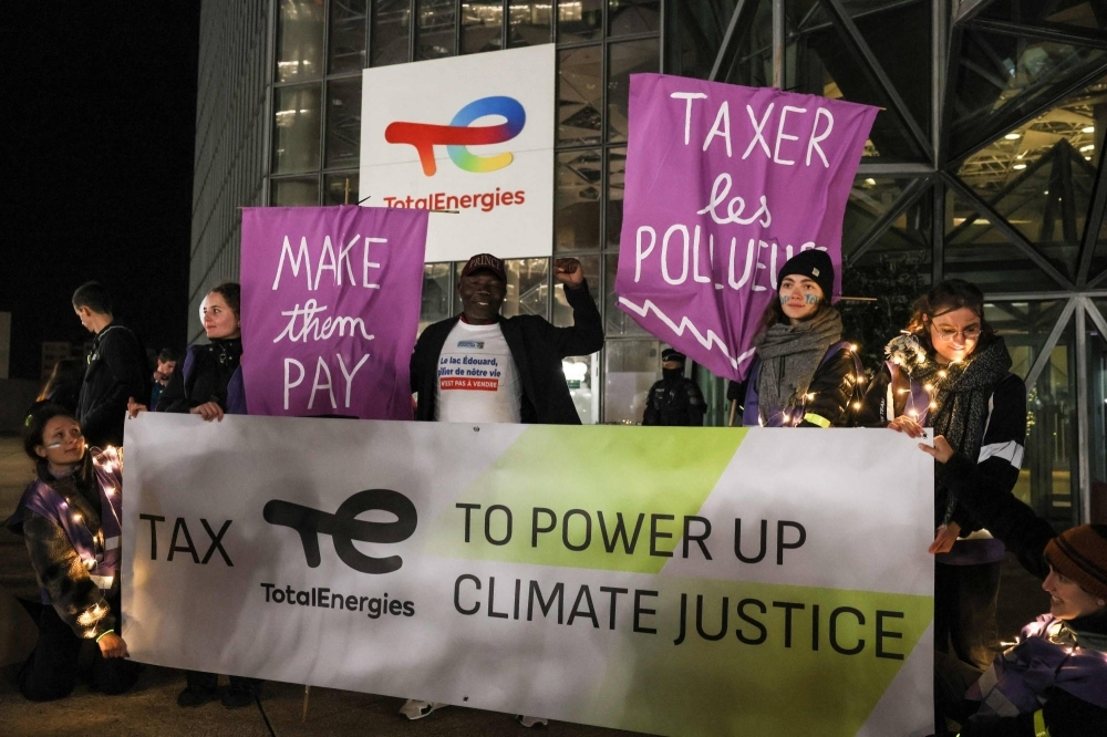 Demonstrators hold banners in front of the TotalEnergies headquarter building at La Defense in Courbevoie, France, on Nov. 3, ahead of the international climate conference COP28 in Dubai later this month.