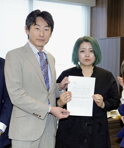 Satoko Nagamura, a representative of Kodomap (right), hands a letter of request to Koji Takahashi, a senior official at the Children and Families Agency, in Tokyo Tuesday.
