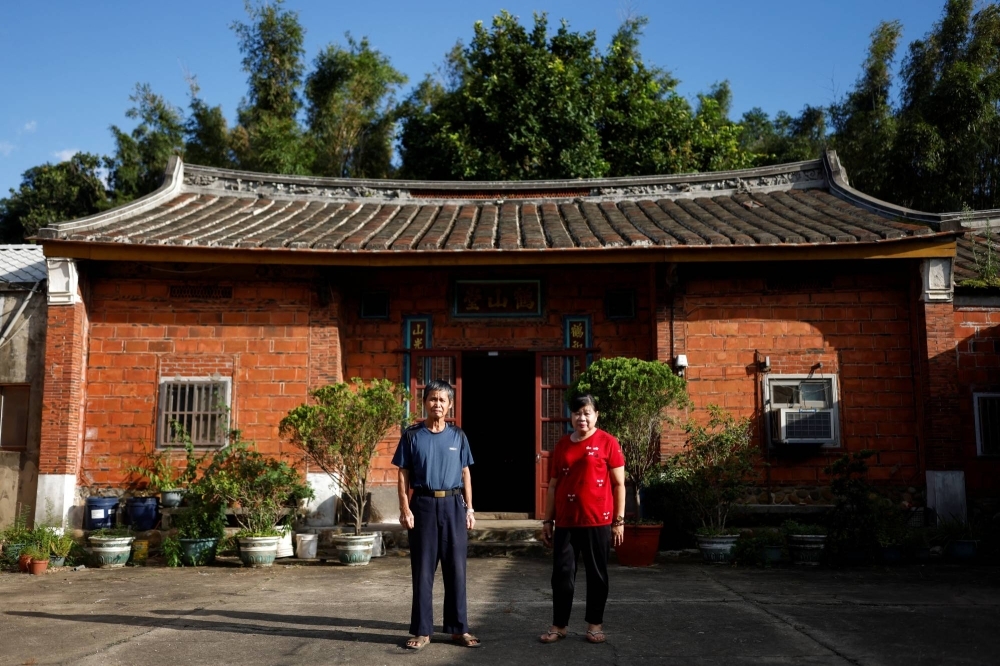 Wei Hsin-hsi and his wife pose for a picture outside their family’s temple that is located inside the proposed expansion area of an industrial park in the Longtan district of Taoyuan, in Taoyuan, Taiwan September 22, 2023. REUTERS/Carlos Garcia Rawlins