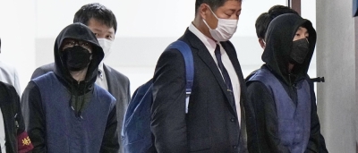 Suspects arrested aboard a flight from Cambodia for their alleged involvement in phone scams arrive at Tokyo's Haneda Airport on Wednesday night.
