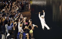 A man dressed as Kentucky Fried Chicken founder Colonel Sanders jumps into the Dotonbori River in Osaka after the Hanshin Tigers won the Japan Series. | KYODO