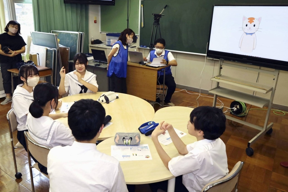 Students at Koshino Junior High School in Fukui Prefecture engage in a discussion with virtual transfer student Himawari-chan (on screen) during a lesson on disaster prevention on Sept. 19.