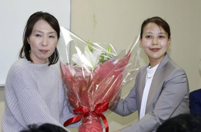 Shoko Kawata (right) receives flowers after winning the Yawata mayoral election in Kyoto Prefecture on Sunday.