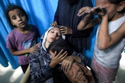 A wounded Palestinian woman from the Baraka family is surrounded by her children upon their arrival at Nasser Hospital in Khan Yunis in the southern Gaza Strip following Israeli airstrikes that hit their building on Monday. 