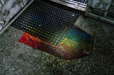 An pride flag is seen under a rubber door mat at an entrance to a basement of an office building in Kherson, Ukraine, in 2022. 