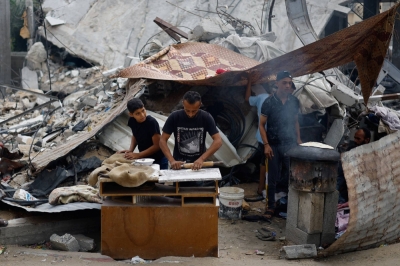 Palestinians prepare food next to destroyed buildings in Khan Younis on Monday.