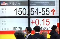 People pass an electronic board showing the rate of the yen against the dollar on a street in Tokyo on Wednesday. | AFP-JIJI