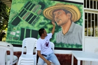 Armando Aroca, environmentalist, former guerrilla and current nursery manager of the Common Community Multi Active Cooperative (COMUCCOM) farm, points to a mural with the image of murdered environmentalist Jorge Santofimio in Puerto Guzman, Colombia, on June 27. | REUTERS