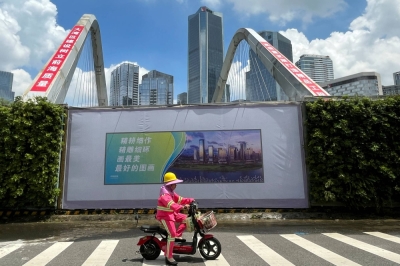 A worker rides a scooter past an unfinished bridge near the center of the Qianhai new district in Shenzhen, Guangdong province, China.