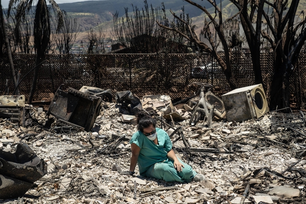 A woman sits where her apartment once stood in Lahaina, Hawaii, after the city was devastated by a wildfire, on Aug. 11. 