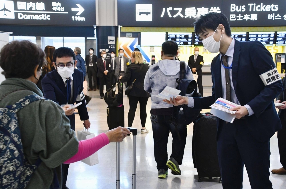 Transport ministry officials hand out fliers to arriving international visitors warning against using unlicensed taxis at Narita Airport in Chiba Prefecture in early November.