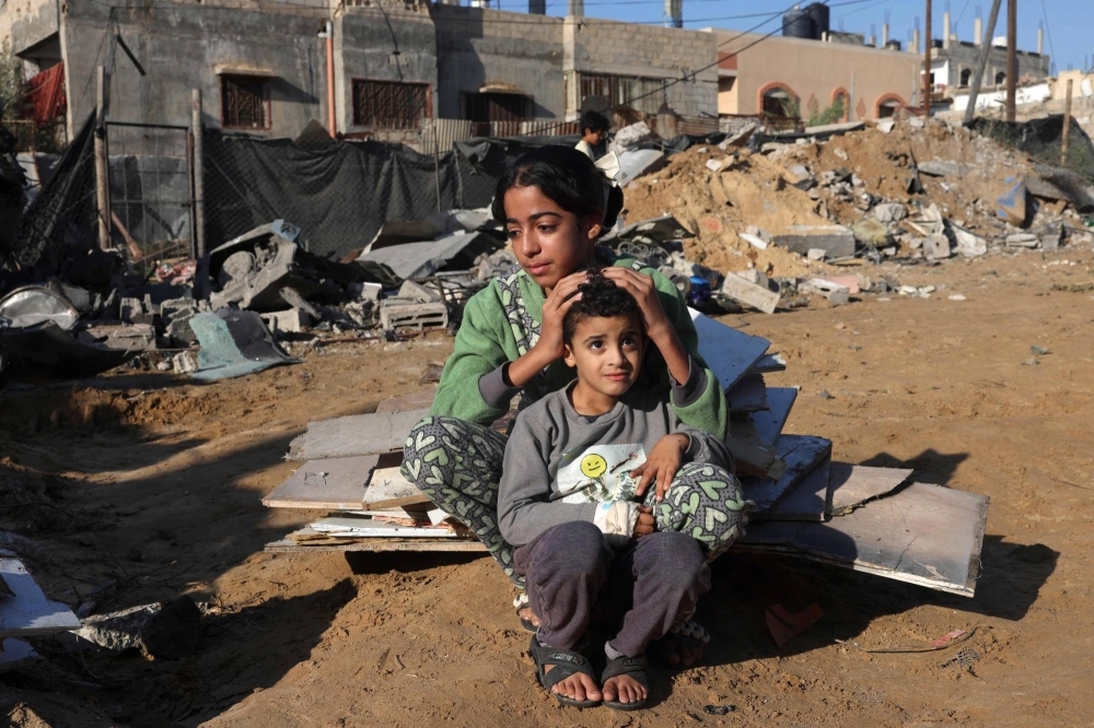 A Palestinian girl and her brother sit amidst the debris of a house following an Israeli strike in Rafah in the southern Gaza Strip on Saturday. 