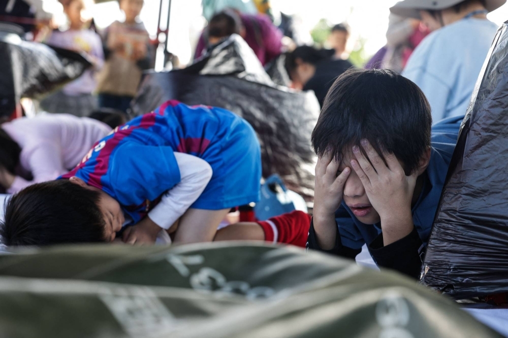 Children take shelter when hearing an air raid sirens during an event held by the Taiwanese civil defense organization Kuma Academy, in New Taipei City on Saturday to raise awareness of natural disaster and war preparedness.