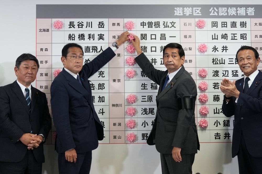 Prime Minister Fumio Kishida and others place a paper rose on an Liberal Democratic Party candidate's name to indicate a victory in the Upper House election, at the party's headquarters in Tokyo in July 2022. 