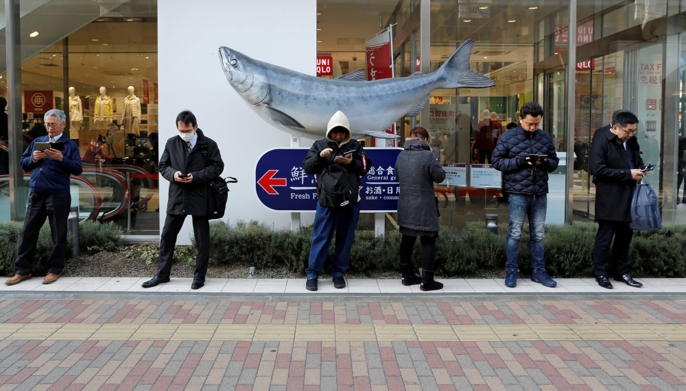 People use smartphones on the street in Tokyo in January 2019.