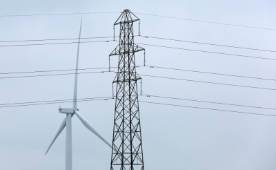A wind turbine and an electricity pylon in Finedon, Britain. Developers can no longer use financial modeling that assumes gas power plants are used constantly throughout their 20-year-plus lifetime, analysts said.