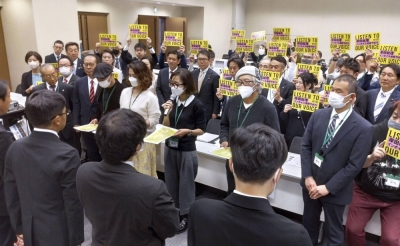 Members of a freelancers group opposing Japan's new invoice system hand documents requesting its abolition to Finance Ministry officials in Tokyo on Nov. 13.