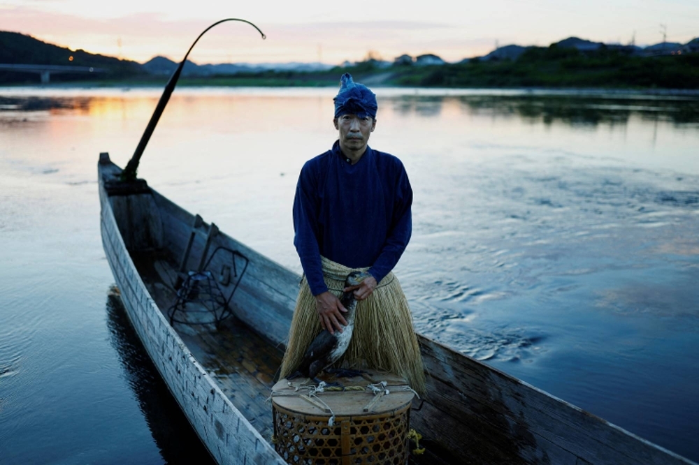 Adachi, 48, poses for a picture with one of his cormorants on Sept. 9. Environmental changes are impacting the traditional method of fishing, leading to smaller and scarcer fish.
