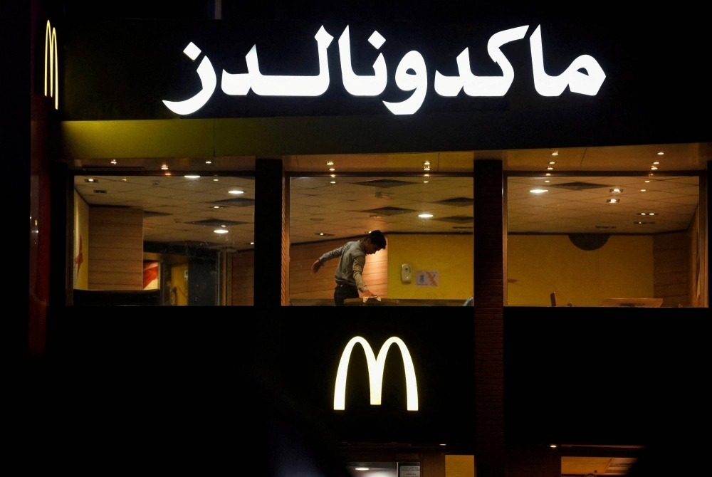 A worker cleans a table in an empty McDonald's restaurant in Cairo on Monday.