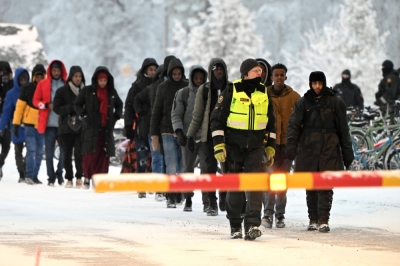 Finnish Border Guards escort migrants at the international border crossing at Salla, northern Finland, on Thursday.