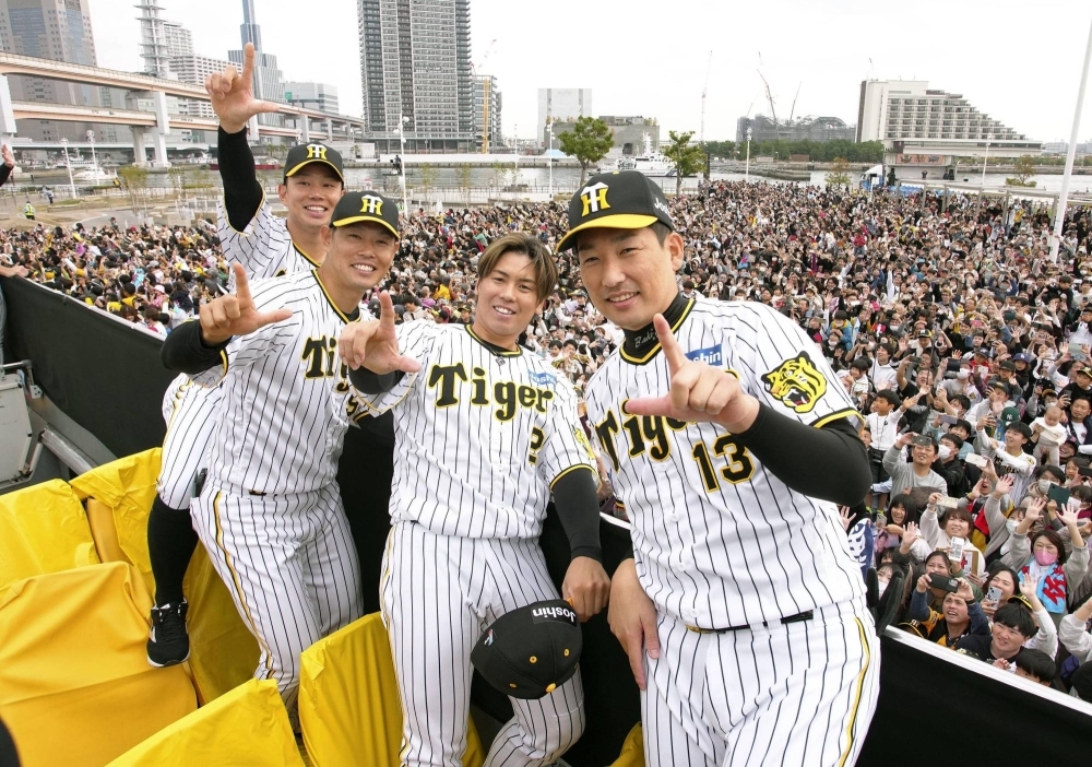 Tigers players Kento Itohara (left), Fumihito Haraguchi (second from left), Ryutaro Umeno (third from left) and Suguru Iwazaki pose for photos during the team's victory parade in Kobe on Thursday.