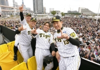 Tigers players Kento Itohara (left), Fumihito Haraguchi (second from left), Ryutaro Umeno (third from left) and Suguru Iwazaki pose for photos during the team's victory parade in Kobe on Thursday. | KYODO