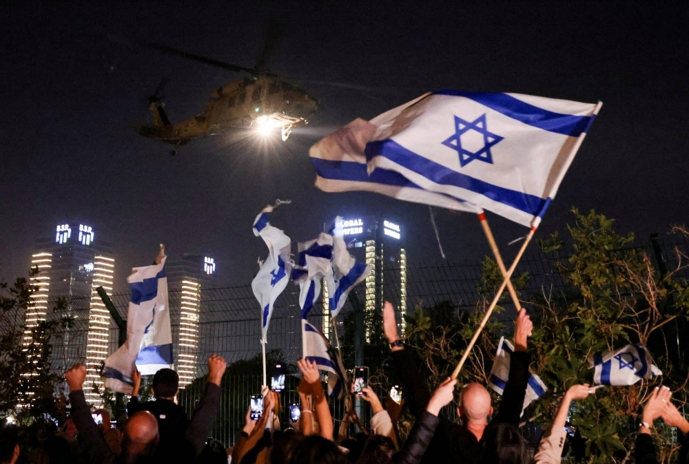 People wave Israeli flags as helicopter carrying hostages released as part of a deal between Israel and Palestinian Islamist group Hamas arrives at Schneider Children's Medical Center in Petah Tikva, Israel, on Friday.