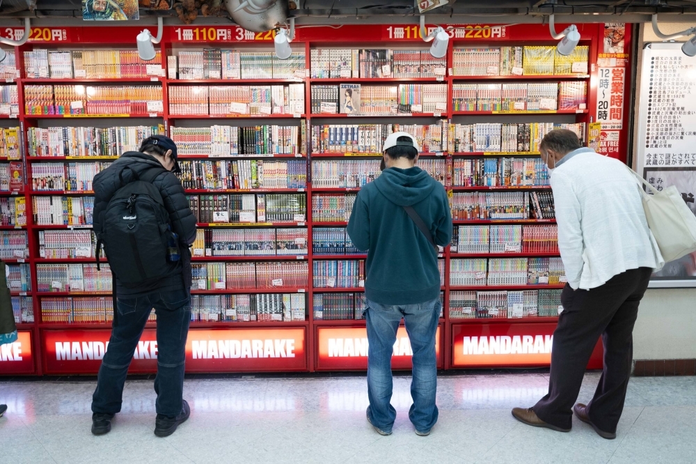 Men stand outside a rack of manga at a store in Tokyo's Nakano Broadway. 