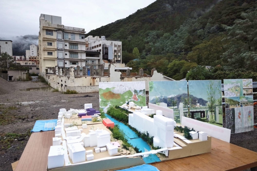 The defunct Ichiyotei Hotel (background), which is undergoing renovation work, and a model of the proposal for the building in Minakami, Gunma Prefecture.