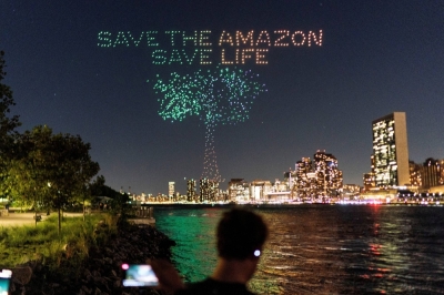 People in New York watch drones creating a 3D display outside the United Nations Headquarters calling attention to the Amazon rainforest and climate change.