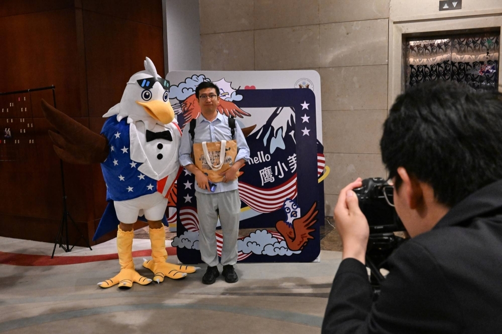 A visitor to an American college fair at a Marriott Hotel in Beijing poses for a souvenir photo next to an eagle mascot on Sept. 23. Students have been traveling between China and the U.S. for generations, propelled by ambition, curiosity and a belief that their time abroad could help them better their and their countries’ futures.