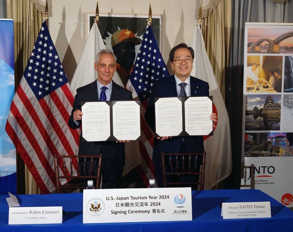 U.S. Ambassador to Japan Rahm Emanuel (left) and tourism minister Tetsuo Saito sign a memorandum of cooperation on tourism promotion on Wednesday in Tokyo.