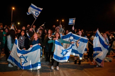 Israeli supporters hold flags hostages arrive at Ofakim army base in southern Israel on Thursday.