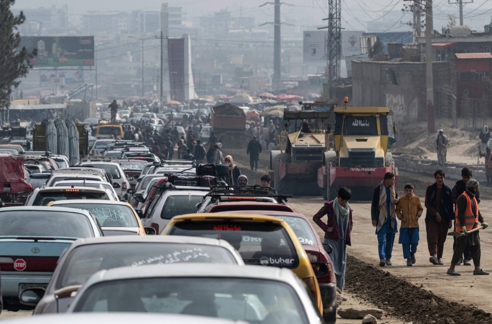 Commuters in Kabul make their way through traffic as construction laborers work on a road on Nov. 21.