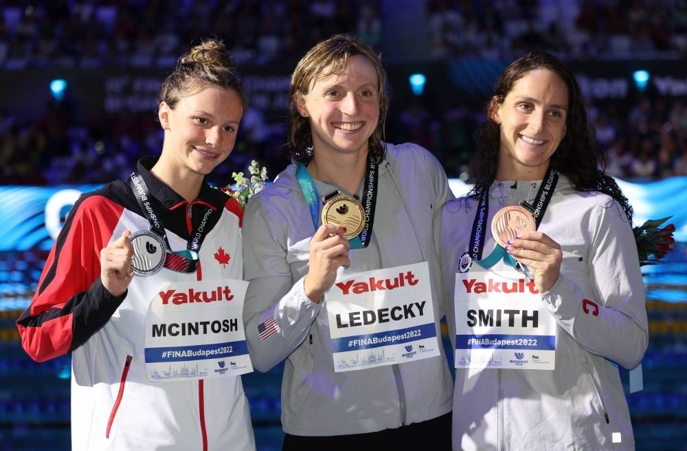 Canada's Summer McIntosh and Katie Ledecky of the U.S. celebrate medal wins with Leah Smith of the U.S. at the FINA World Championships in Budapest in June 2022.