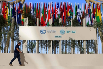 A man walks past national flags of participating countries at the venue of the COP28 climate summit in Dubai on Thursday.