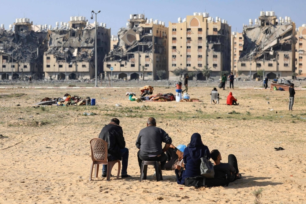 Residents of the Qatari-funded Hamad Town residential complex in Khan Younis, in the southern Gaza Strip, sit with some of their belongings as they flee their homes after an Israeli strike, on Saturday.