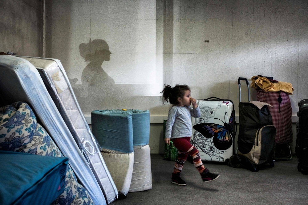 A girl walks among bags and mattresses as Eastern European migrants wait to temporarily settle in a locale in Decines, France, in 2015. Some of the world's richest countries saw a sharp rise in child poverty from 2014 to 2021, according to a UNICEF report.