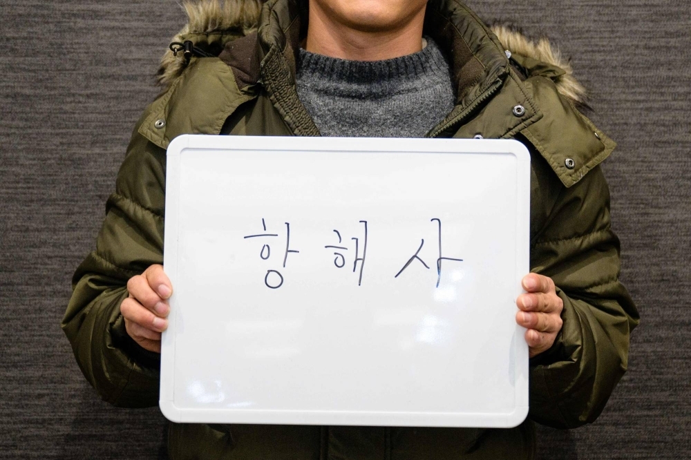 Kim, 31, who loaded his family into a homemade wooden boat in May and sailed away from his native North Korea, attends a job fair for North Korean defectors in Seoul while holding a whiteboard that reads "Navigator."