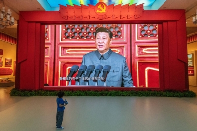 A young boy watches a screen showing Chinese President Xi Jinping at the Military Museum in Beijing.