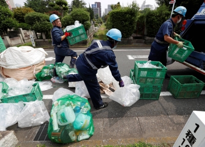 Workers collect recyclable garbage including plastic bottles on World Environment Day in Tokyo in June 2020.  