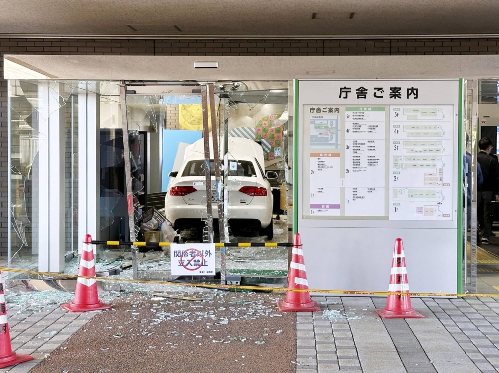 A photo supplied by a witness shows a car inside the main entrance of the village office of Tokai, Ibaraki Prefecture, on Wednesday.