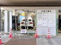 A photo supplied by a witness shows a car inside the main entrance of the village office of Tokai, Ibaraki Prefecture, on Wednesday. | Kyodo