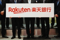 Rakuten Bank executives hold a placard showing the company logo during a ceremony to mark the company's debut on the Tokyo Stock Exchange on April 21. | REUTERS