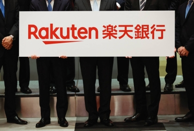 Rakuten Bank executives hold a placard showing the company logo during a ceremony to mark the company's debut on the Tokyo Stock Exchange on April 21.