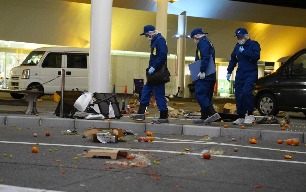 Police officers examine the site of a car crash in a square in front of the Hitachi municipal offices in Ibaraki Prefecture on Wednesday.