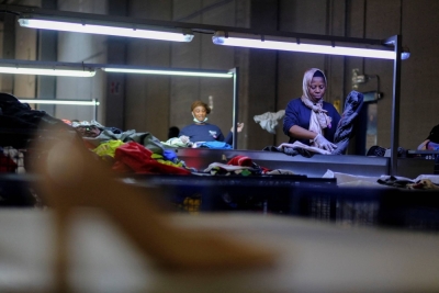Workers organize used clothing for packaging at a warehouse near Barcelona on Aug. 1.