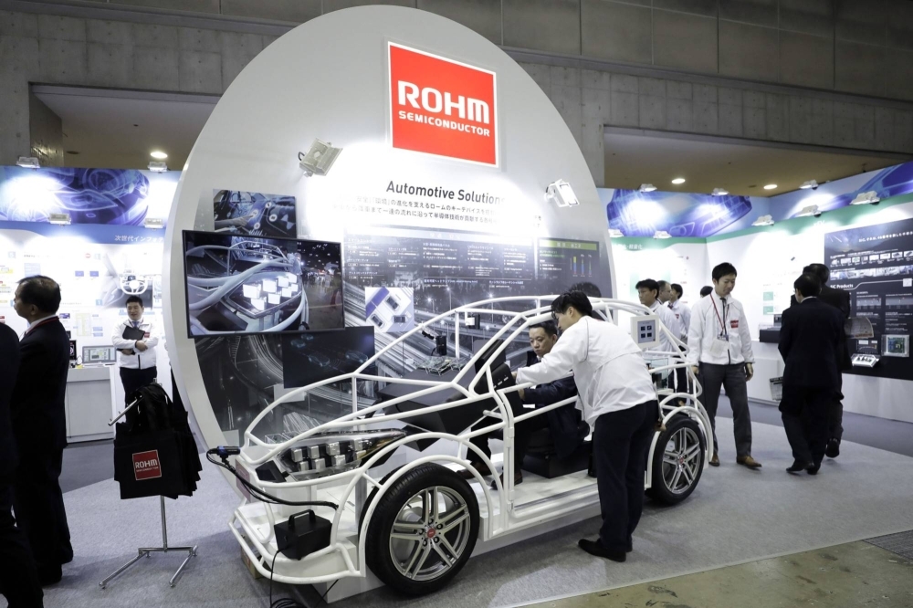 A seated attendee examines an automotive solution system using Rohm semiconductor products at the Automotive World 2018 forum in Tokyo in January 2018.