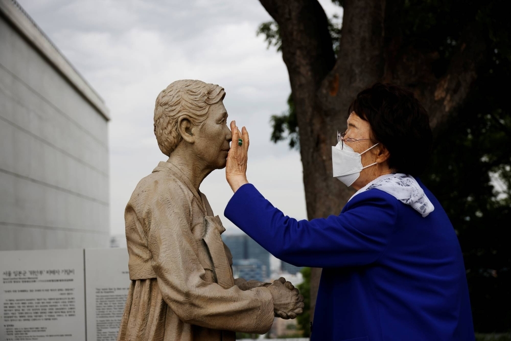 Former South Korean "comfort woman" Lee Yong-soo with a statue symbolizing "comfort women" at the Seoul Comfort Women Memorial